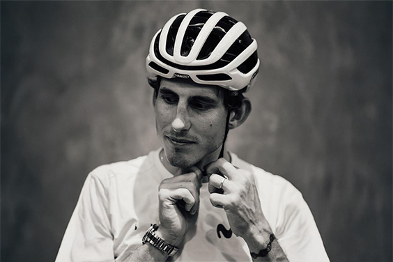 Professional racing cyclist from the Movistar team puts on a black and white AirBreaker 2.0 and fastens the chin strap &copy; ABUS