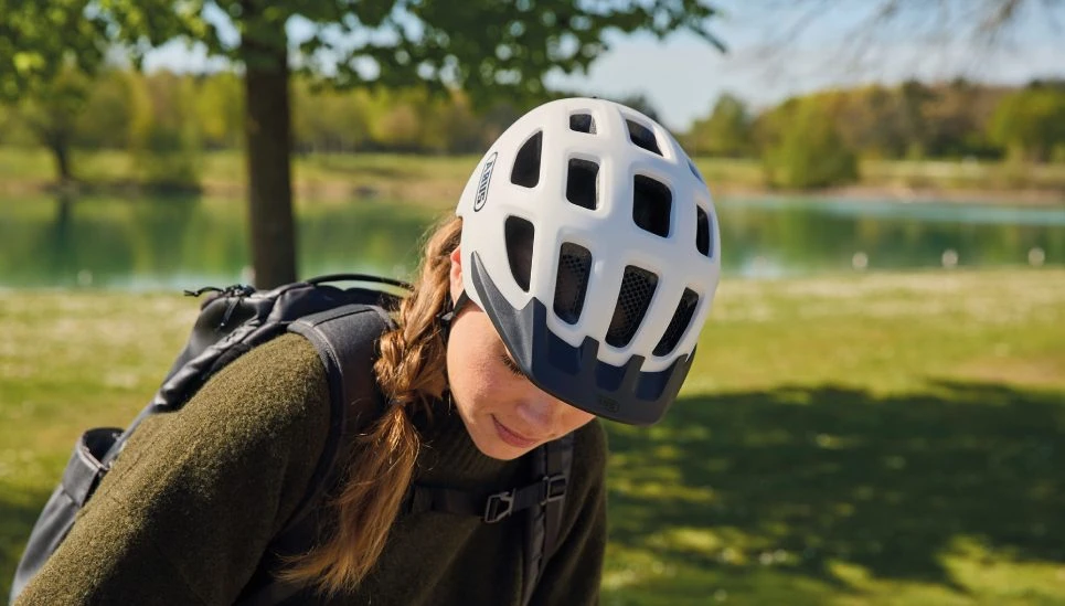 A woman with her head bowed is wearing a YOUN-I 3.0 ACE bicycle helmet with a removable visor © ABUS