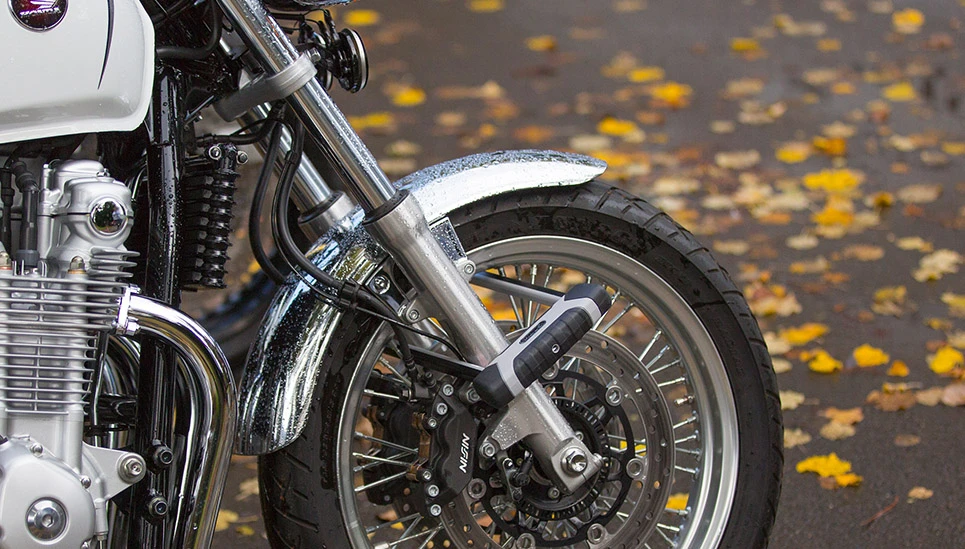 Het voorwiel van een motor wordt vastgezet met een U-slot dat door de spaken en rond de verende voorvork loopt. ©ABUS