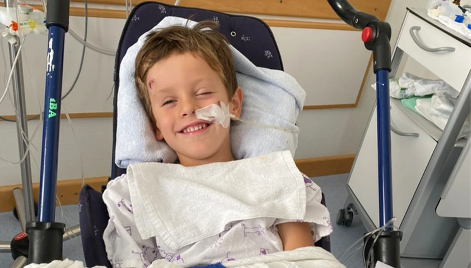 Lächelndes Kind im Krankenbett, das medizinisch versorgt wird © ABUS