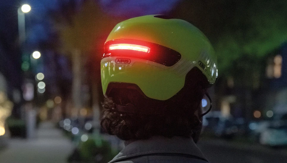 Rückansicht des urban Fahrradhelm HUD-Y in signal yellow mit rot leuchtendem Rücklicht. © ABUS