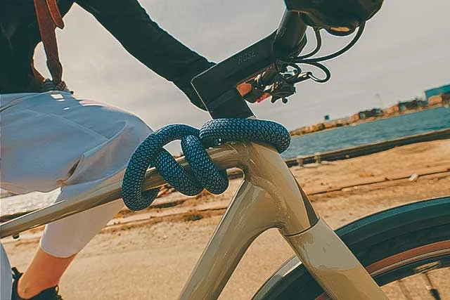 YARNIT kettingslot denimblauw om het frame van een fiets gewikkeld tijdens het fietsen © ABUS