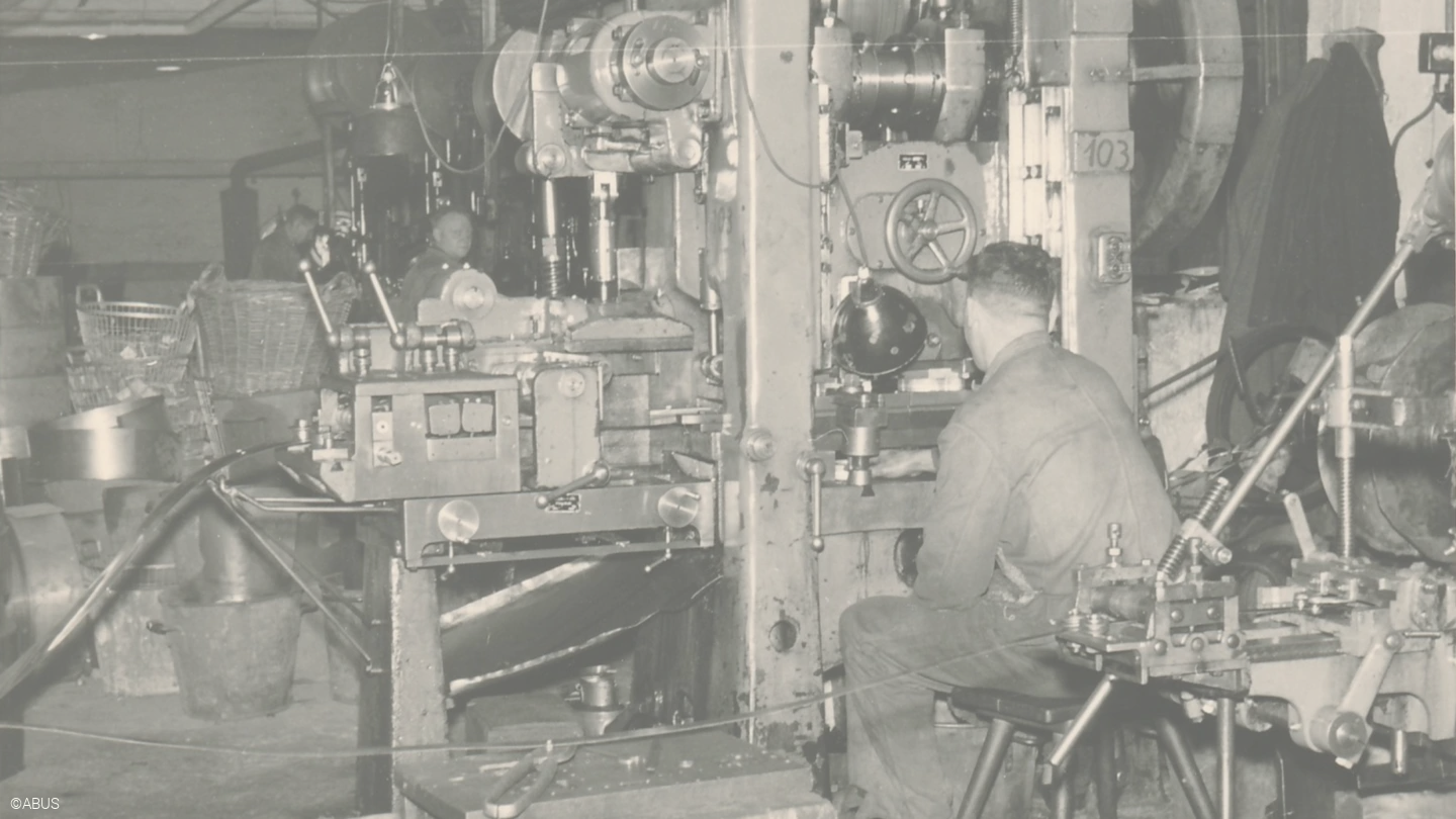 Een man zit en werkt aan een machine © ABUS