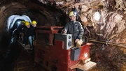 Fahrt durch den Stollen mit der Grubenbahn: auf dem Anhänger sitzen lachende Kinder mit gelben Helmen.