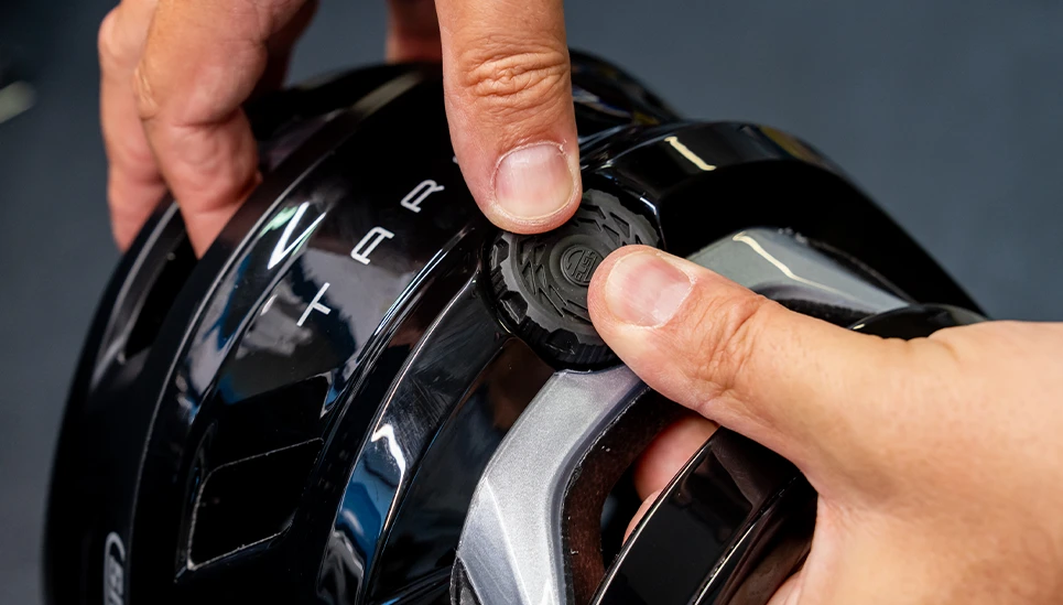 Detailopname: handen stellen het verstelsysteem van de MTB-helm Targon af © ABUS