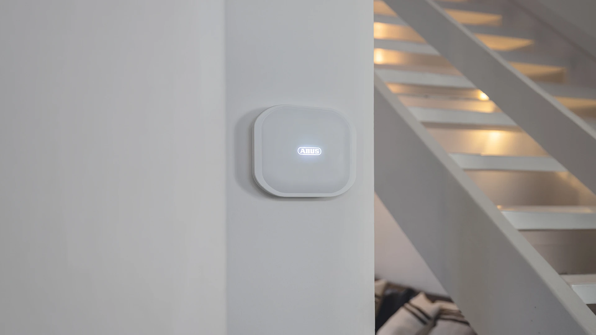 The Comfion Pro control unit is mounted on an interior wall. The ABUS logo is illuminated in white.