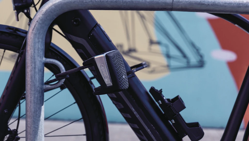 Das ABUS BORDO™ One 6500A Faltschloss an einem Metall-Fahrradständer gesichert © ABUS