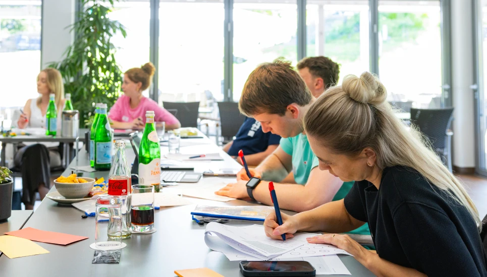 Mitarbeitende sitzen in einer Weiterbildung und schreiben auf einem Block © ABUS