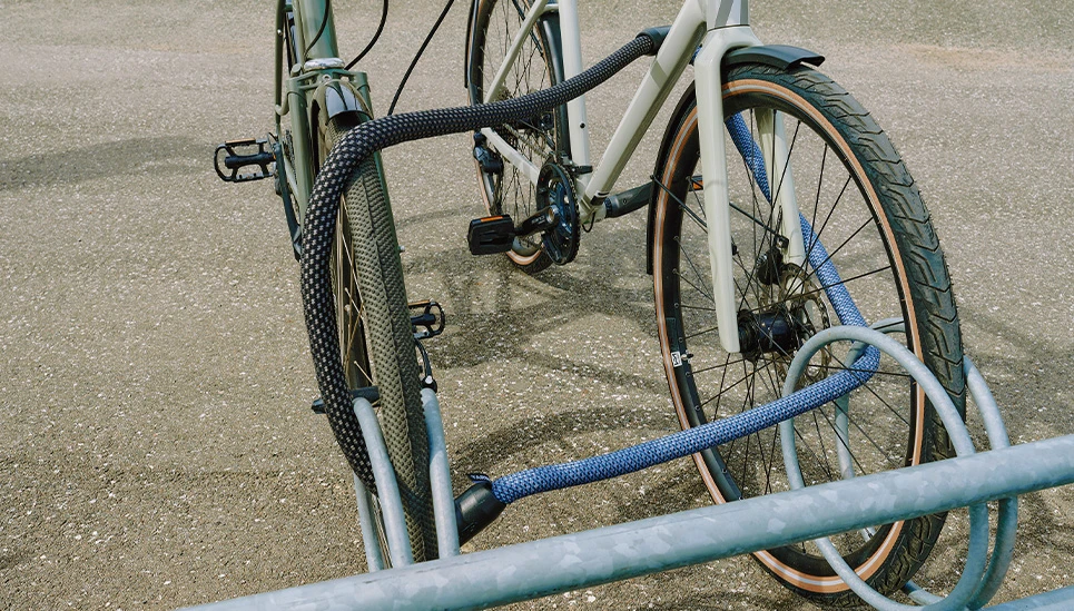 Twee YARNIT-kettingsloten in denimblauw en zwart aan elkaar bevestigd om twee fietsen te beveiligen © ABUS
