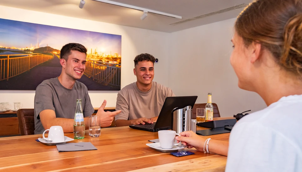 „Auszubildende und Auszubildender im Gespräch während eines Meetings © ABUS