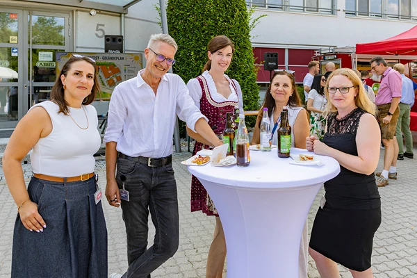 Mitarbeitende stehen an einem weißen Stehtisch bei einem Firmensommerfest © ABUS