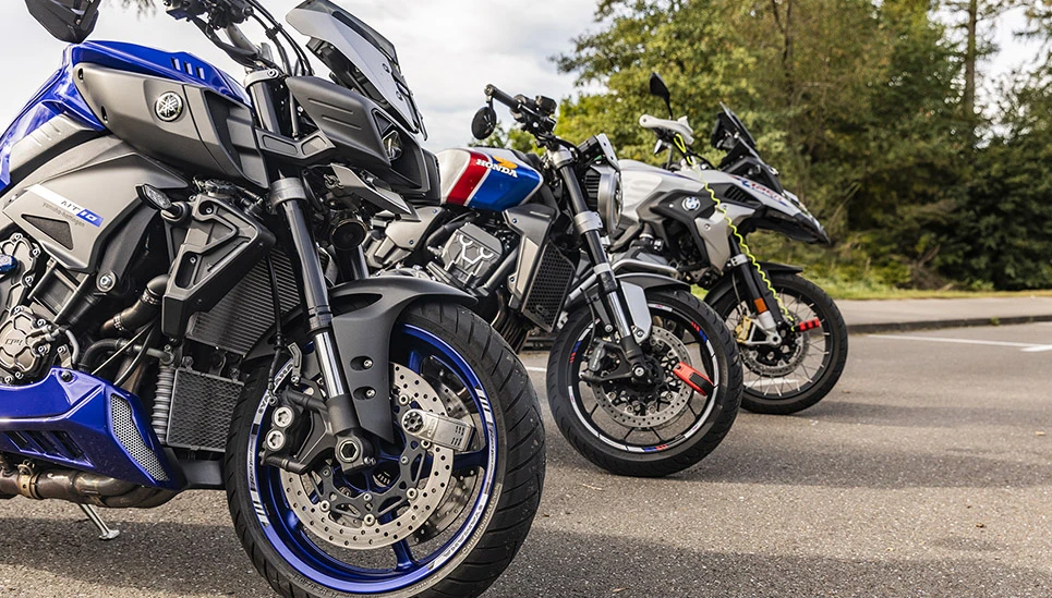 Trois motos sont garées les unes à côté des autres, toutes sécurisées par des serrures à disque de frein - l'une d'entre elles étant également équipée d'un câble à mémoire. ©ABUS