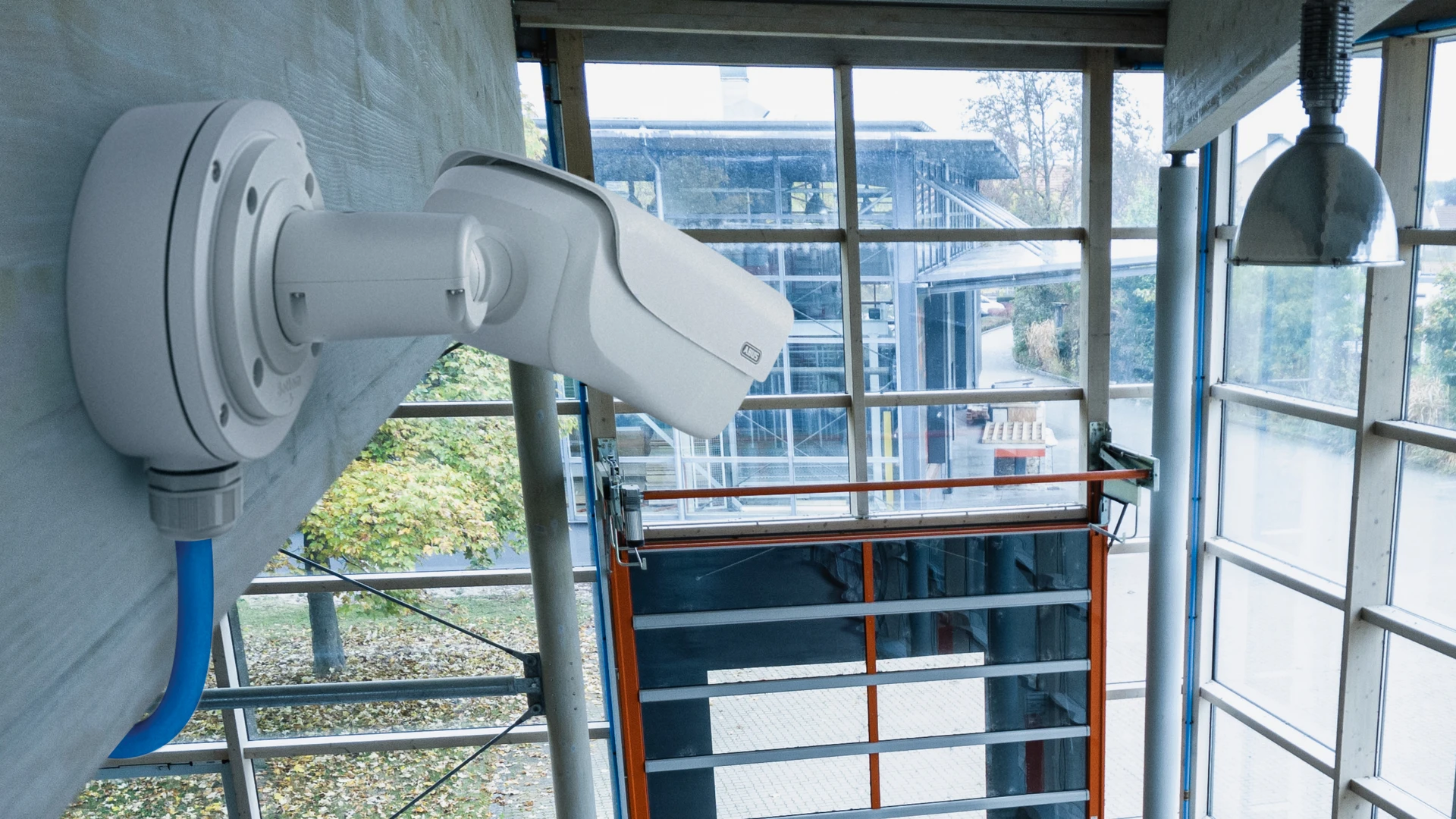 Videoüberwachungskamera von ABUS, ausgerichtet auf den Eingang eines Firmengebäudes.