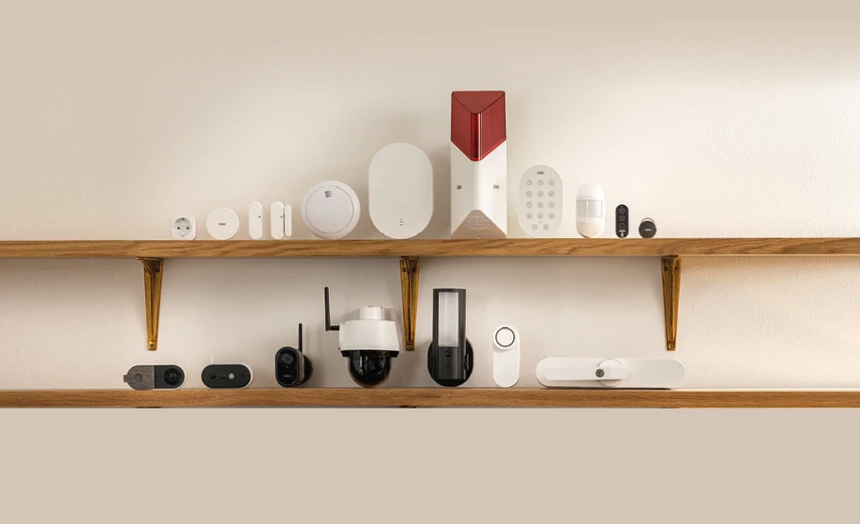 Het volledige Smartvest Pro-assortiment, inclusief compatibele camera's en de ABUS One-uitbreiding, gepresenteerd op twee planken.