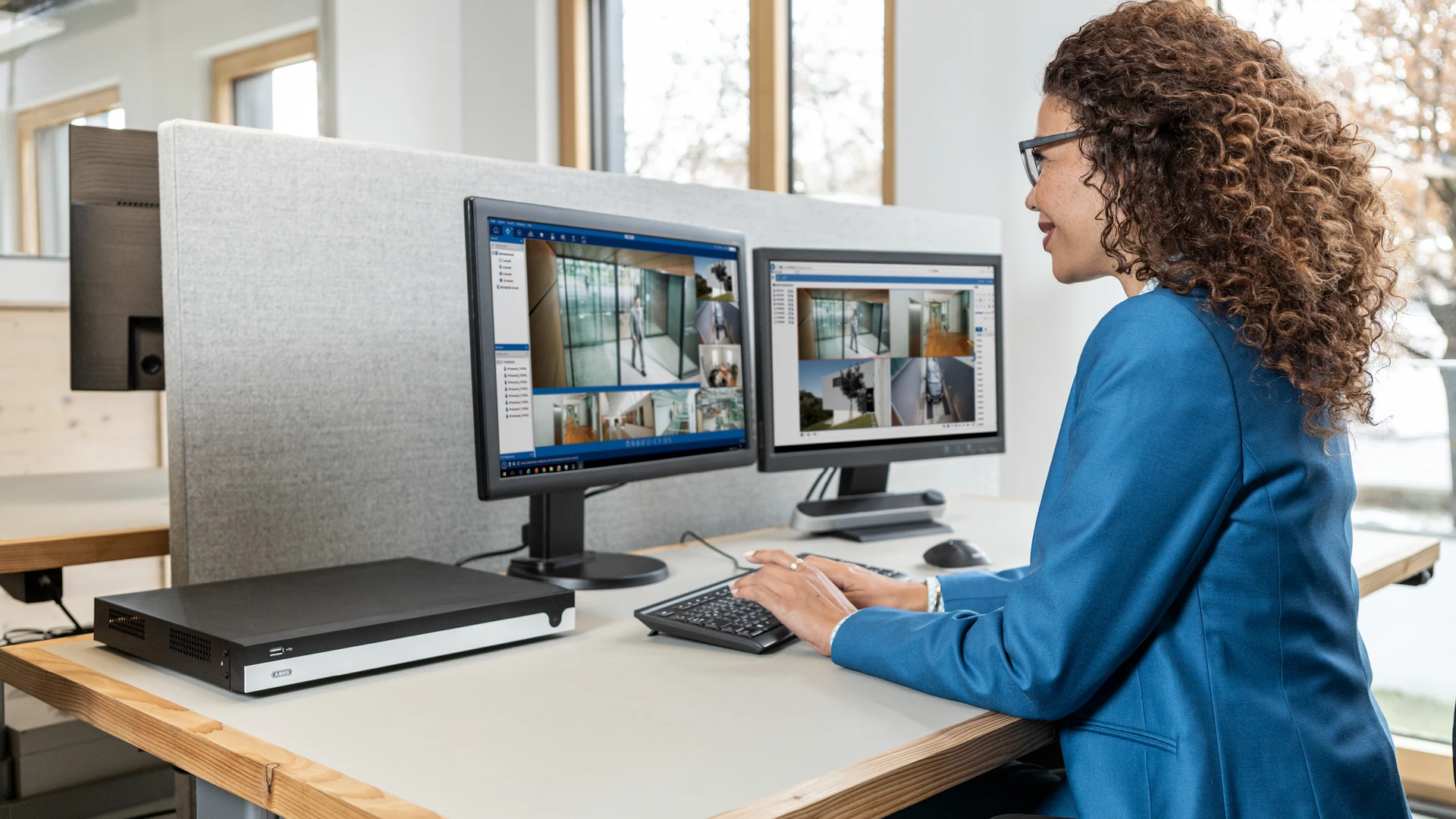 A woman sitting in front of two monitors displaying images from security cameras
