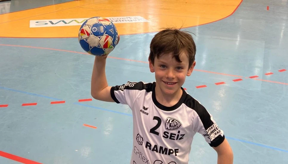 Kleiner Junge lächelnd beim Handball spielen © ABUS