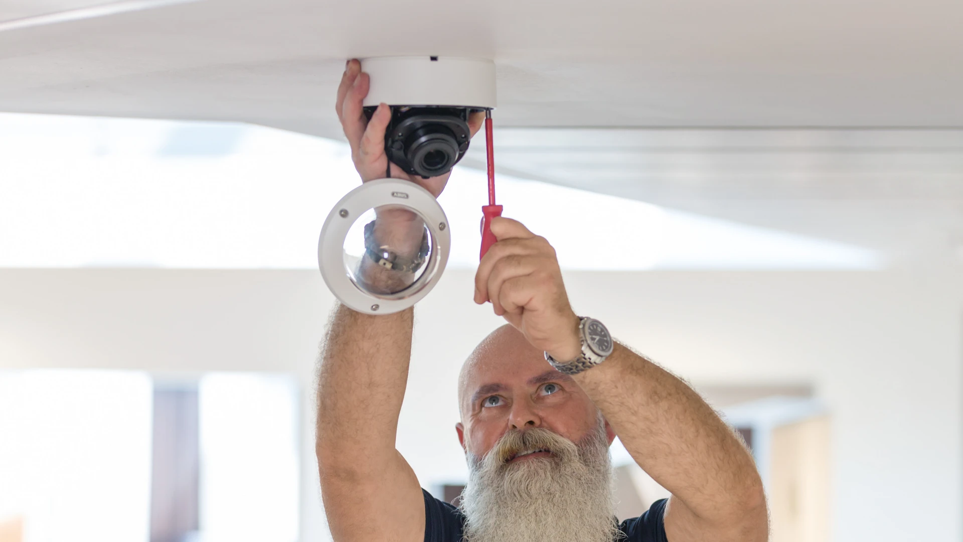 Mann montiert Kamera an Zimmerdecke