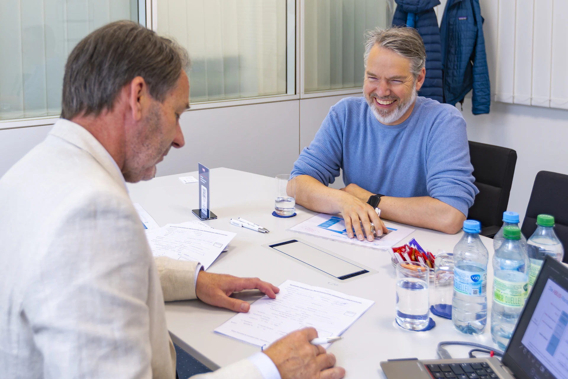 Zwei Mitarbeiter sitzen an einem Schreibtisch mit Unterlagen vor sich liegend zur Besprechung © ABUS