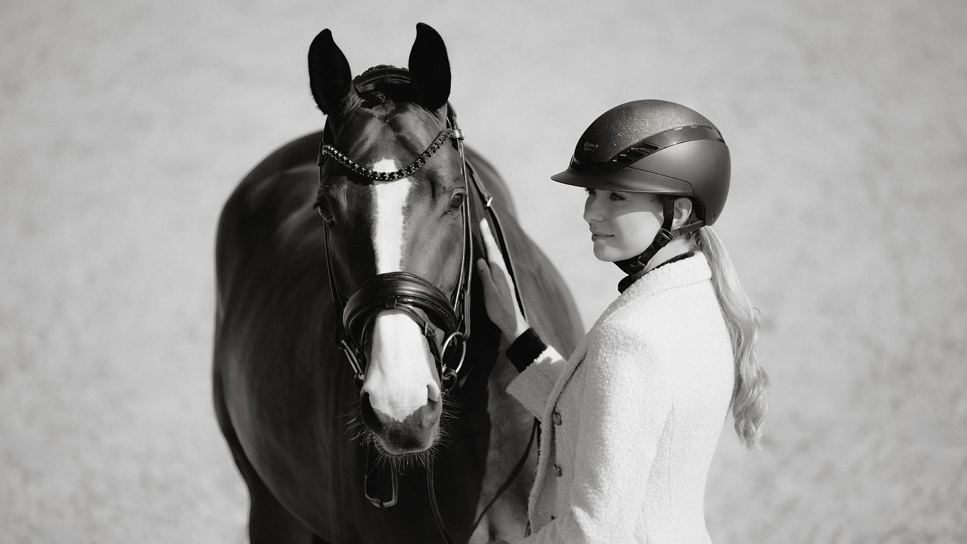 Eine Frau trägt den Reithelm AirLuxe Supreme Glam und steht neben einem Pferd. ©ABUS