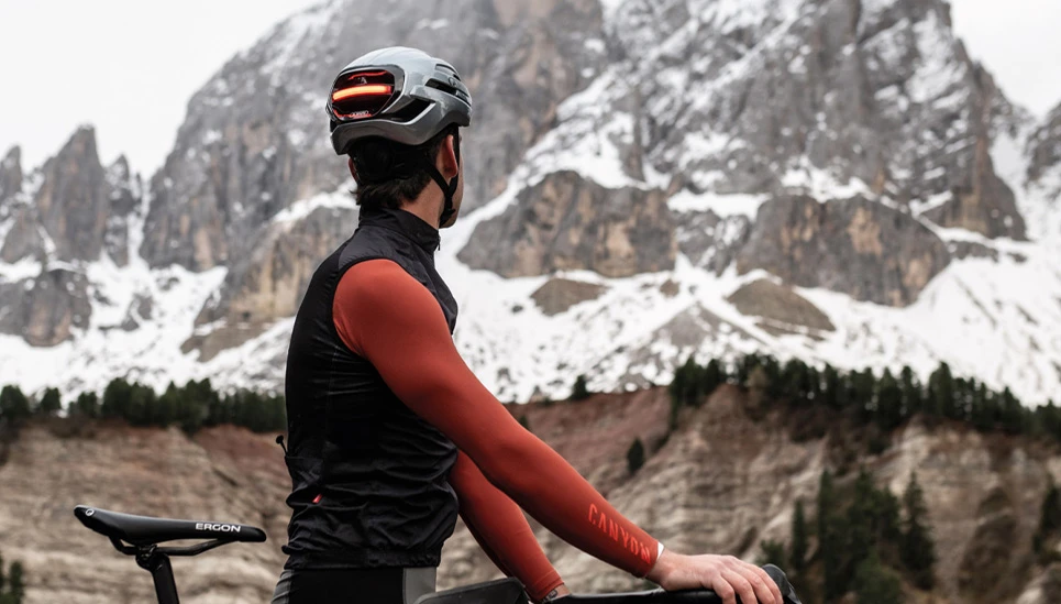 Man wearing a graphite silver Taipan gravel bike helmet looks at mountains in the distance © ABUS