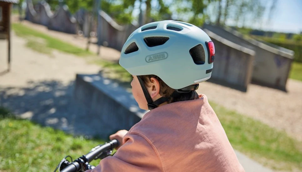 Close-up of a boy sitting on a bicycle and wearing the YOUN-I 3.0 cycle helmet in powder green © ABUS