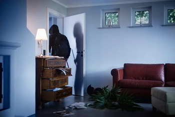 Einbrecher durchsucht Wohnzimmer in der Nacht © ABUS