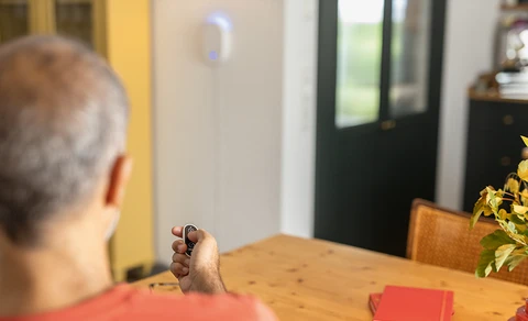 Elderly man operates the Smartvest alarm panel using the remote control.
