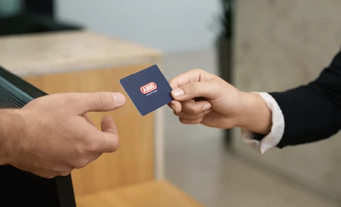 Eine blaue Transponderkarte wird übergeben.