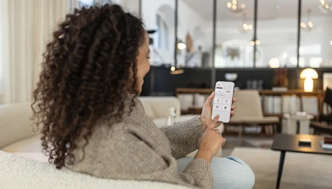 Frau betrachtet das Display ihres Smartphones mit der Comfion App.
