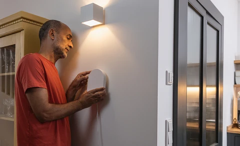 Un homme monte le panneau d'alarme Smartvest Pro sur un mur intérieur.