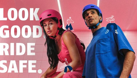 Twee personen dragen de stedelijke fietshelm ABUS XOXO, verkrijgbaar in roze en blauw. Op de achtergrond staat de slogan 'LOOK GOOD RIDE SAFE' © ABUS