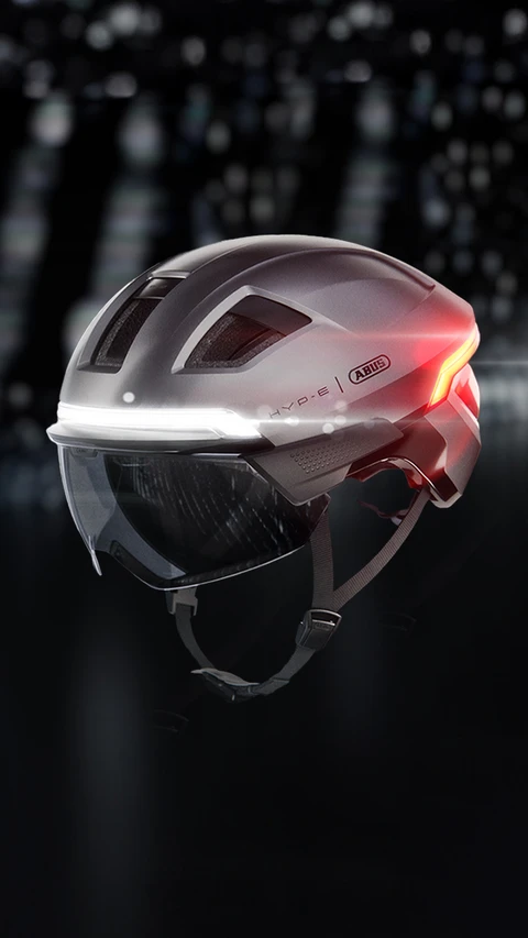 Product image of the HYP-E urban bike helmet (Gleam Silver) with visor, front and rear lights on © ABUS