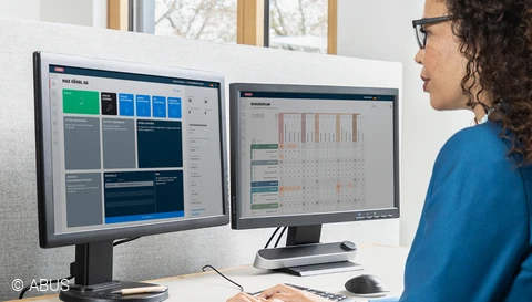 Eine Frau vor zwei Monitoren, auf den der TECTIQ-Schließplan zu sehen ist. © ABUS