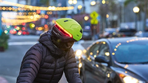 Mann mit urabn Fahrradhelm HYP-E in Signal Yellow mit Fron- und Rücklicht in der Stadt © ABUS