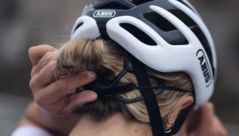 Fahrerin stellt den ABUS AirBreaker 2.0 am Verstellrad ein; sicherer Sitz über dem Dutt © ABUS