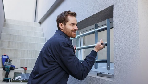 Ein Mann bringt ein ABUS Fenstergitter an. ©ABUS