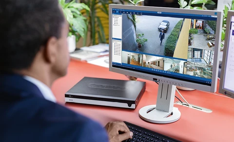 Ein Mann blickt auf einen Monitor mit verschiedenen Live-Bildern von Kameras.