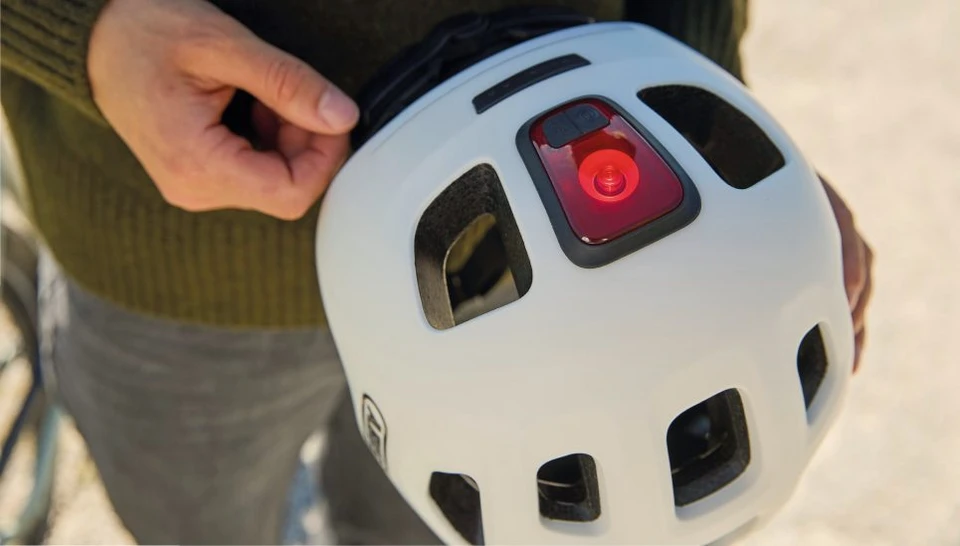 Close-up of the YOUN-I 3.0 ACE bicycle helmet in off-white, viewed from above. Focus on the red taillight © ABUS