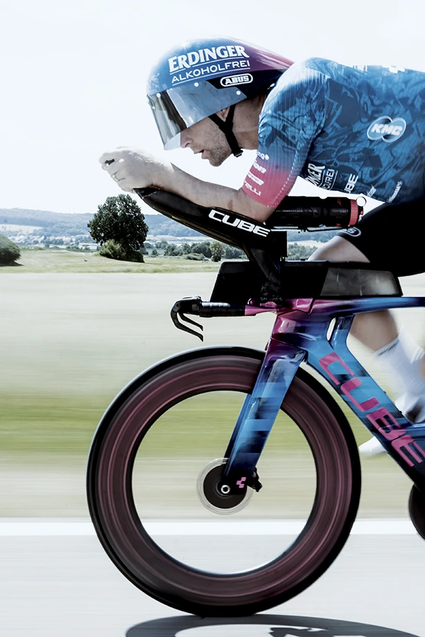 Frederic Funk i aerodynamisk position på en tempocykel under ett cykellopp, utrustad med den nya ABUS TT-hjälmen och sponsorlogotypen ERDINGER Alkoholfrei © Tom Meyer