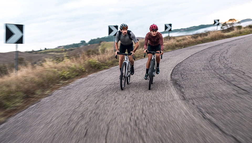 Two cyclists with the ABUS PowerDome moss green and blaze red on a road in Tuscany ©ABUS