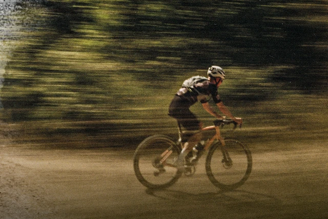 Ciclista gravel con casco Taipan Gravel mentre pedala su una pista forestale polverosa © ABUS