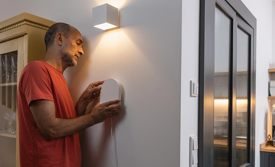 Een man monteert het Smartvest Pro alarmpaneel op een binnenmuur.