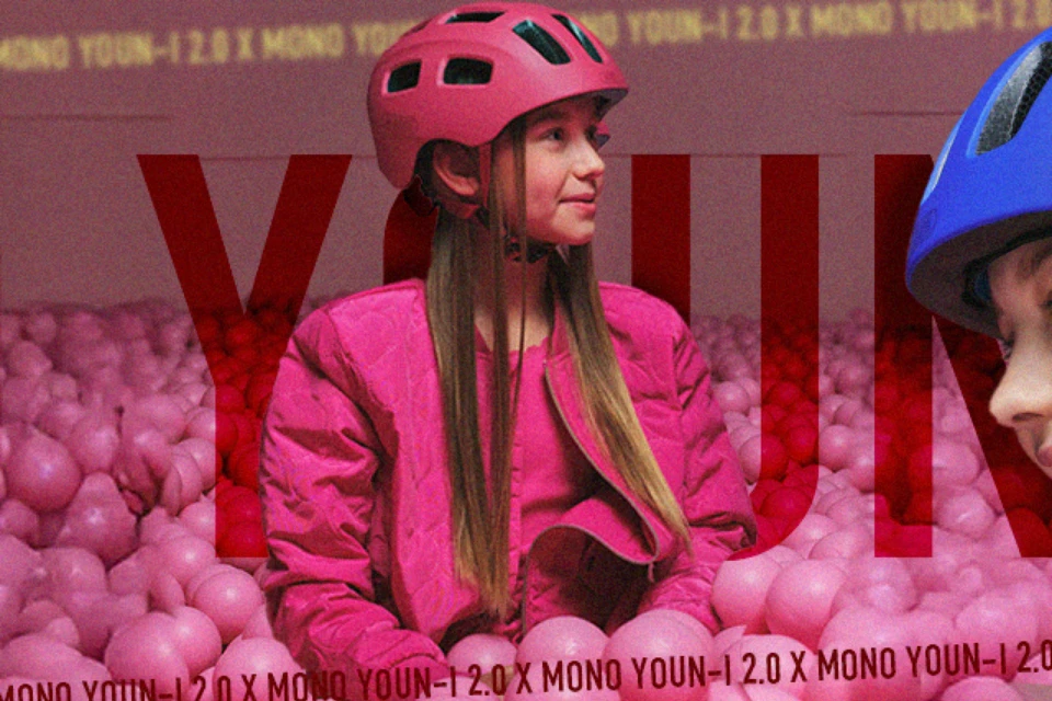 Lächelndes Mädchen mit dem Kinderhelm YOUN-I 2.0 in der Farbe Mono red im pinken Bällebad © ABUS