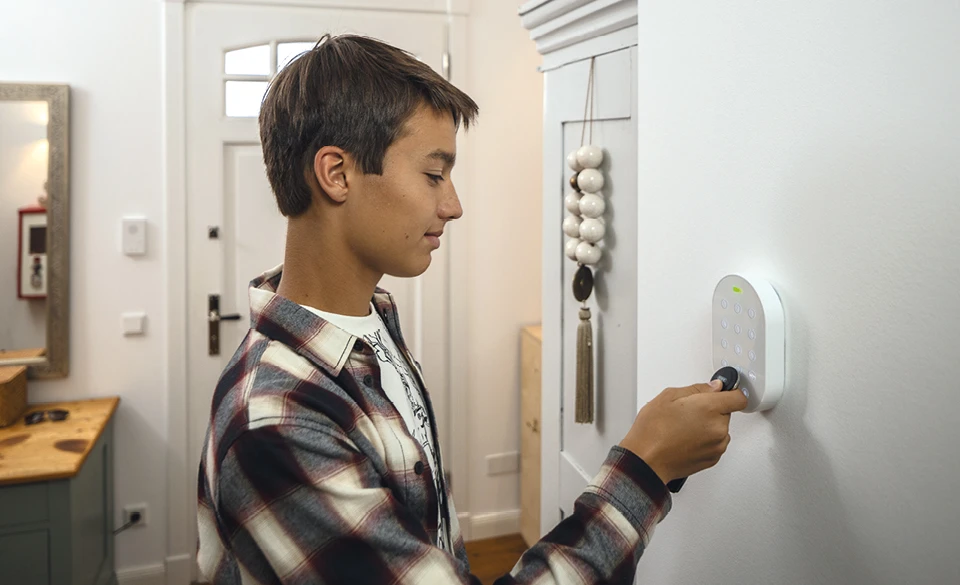 Le garçon s'identifie au panneau d'alarme Smartvest Pro à l'aide de son porte-clés d'identification.