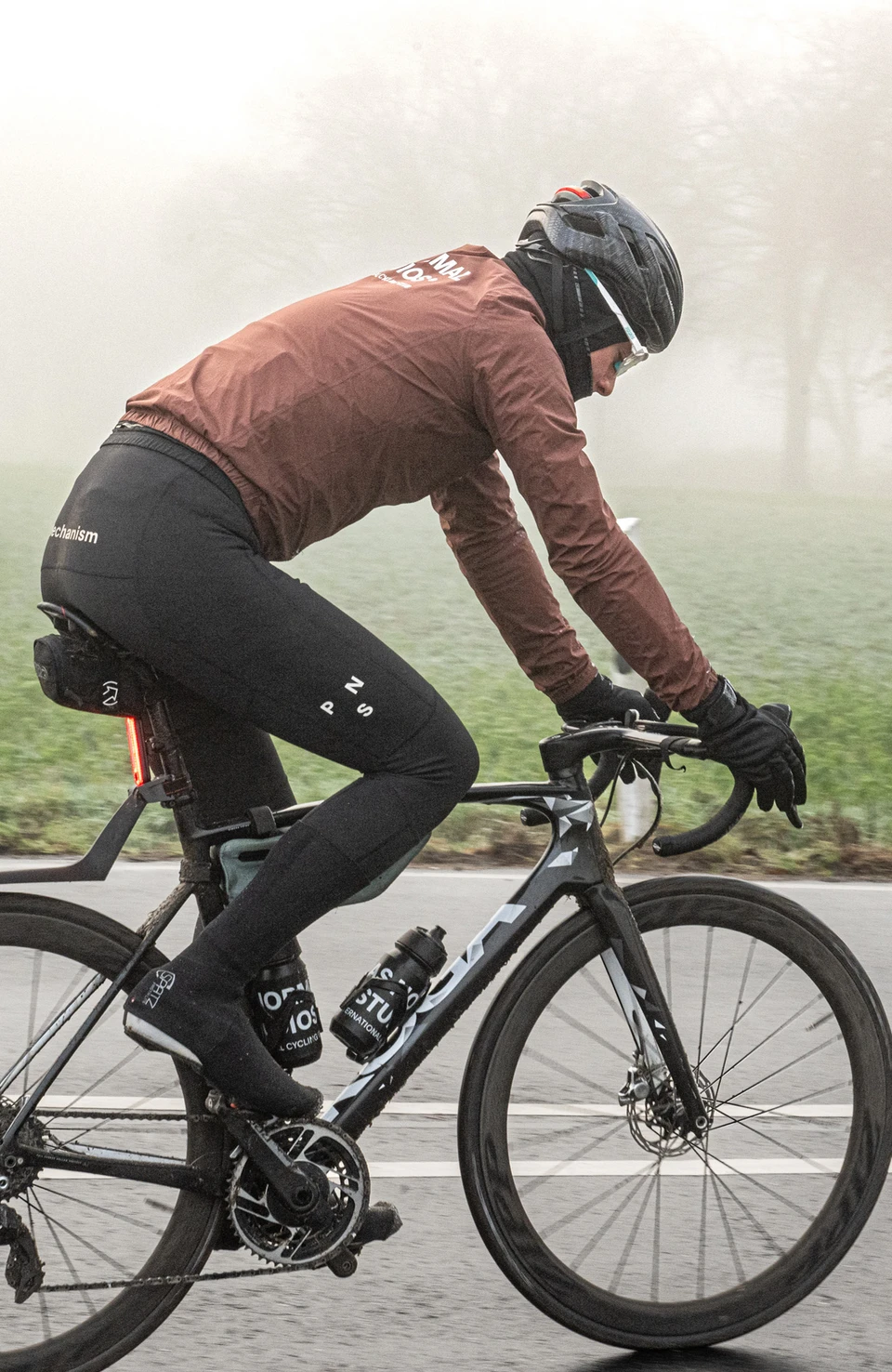 Un ciclista indossa il casco da bicicletta Taipan LED e pedala su una strada di campagna in condizioni di nebbia © ABUS