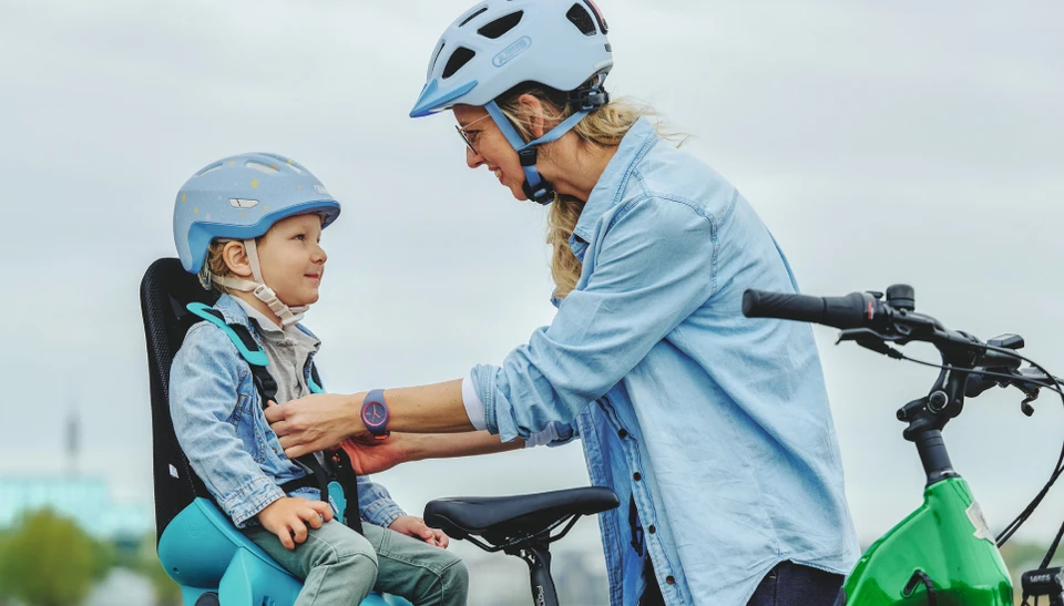 Mutter mit ABUS Aduro 3.0 Helm schützt Kind mit ABUS Smiley 3.0 FL.ACE LED im Fahrradsitz © ABUS
