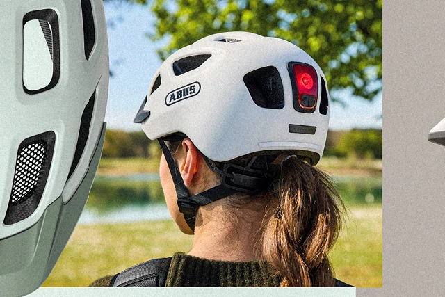 Woman seen from behind wearing a gray ABUS Youn-I 3.0 ACE bicycle helmet and a bright LED taillight © ABUS