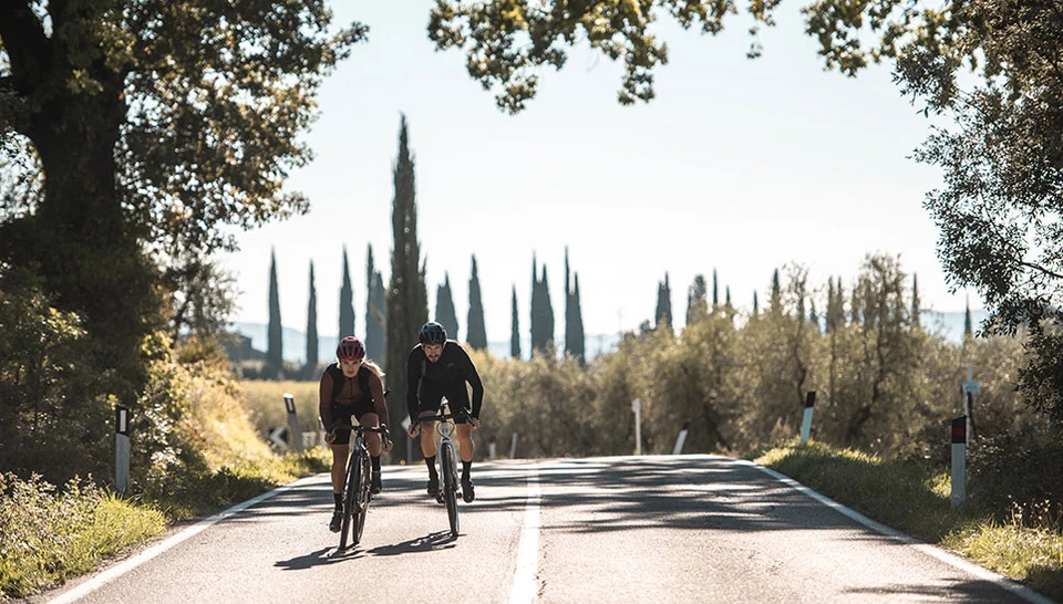 Two cyclists with the ABUS PowerDome moss green and blaze red on a road in Tuscany ©ABUS
