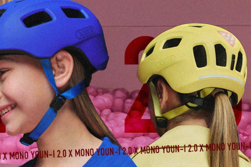 Zwei Mädchen mit dem Kinderhelm YOUN-I 2.0 in den Farbe Mono blue und Mono yellow im pinken Bällebad © ABUS