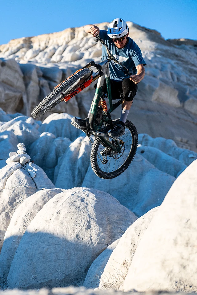 Mountainbiker springt über helle Felsen in karger Landschaft © ABUS